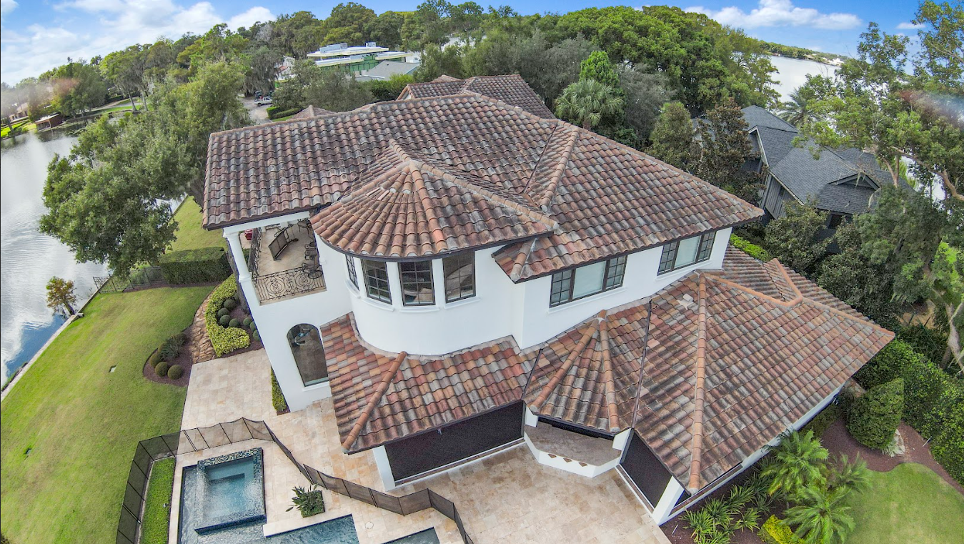 An aerial view of a large house with a tiled roof and a pool