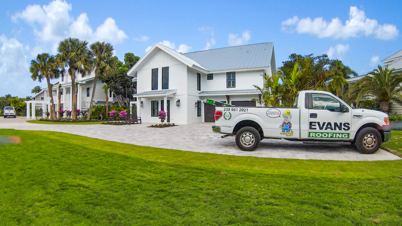 A white truck is parked in front of a large white house