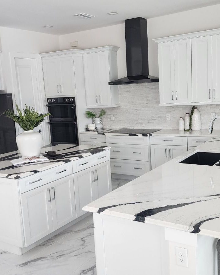 A kitchen with white cabinets and black counter tops.