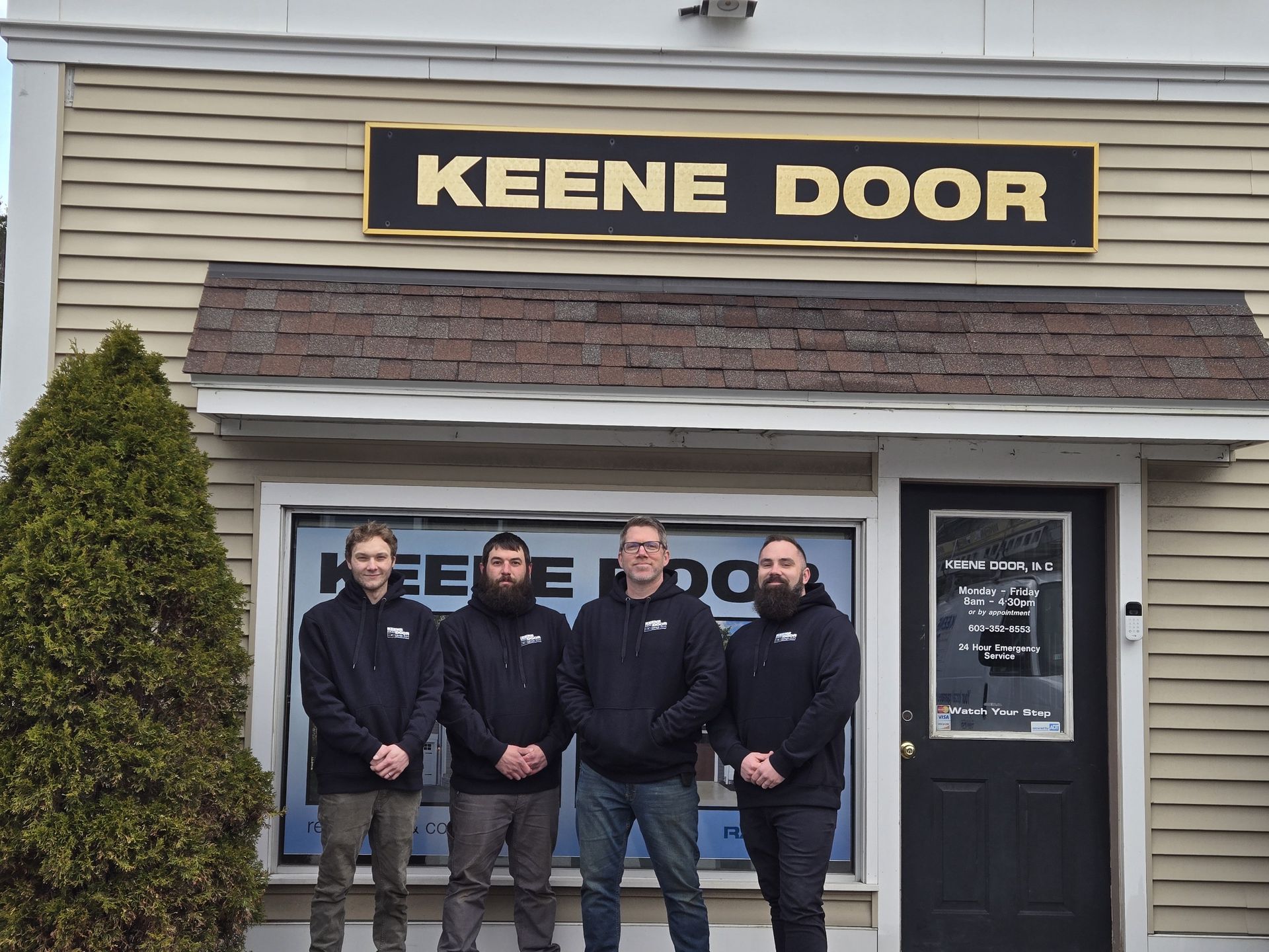 A group of men standing in front of a building that says keene door
