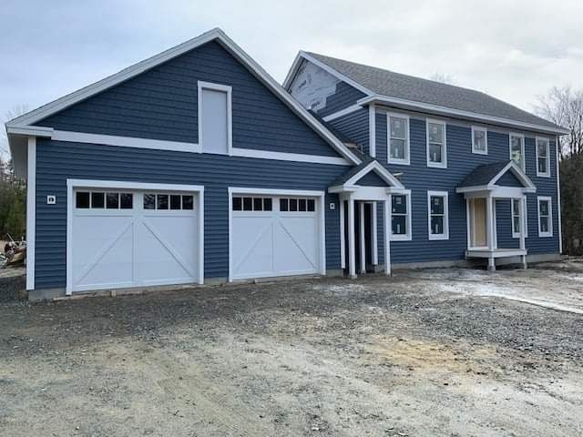 A large blue house with two white garage doors and a porch.