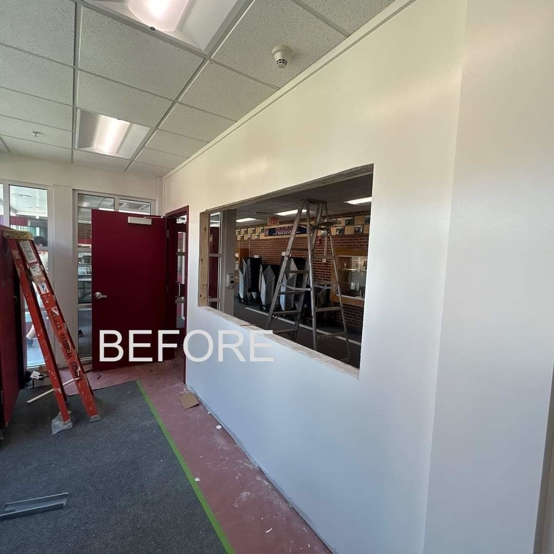 A before picture of a room with a window and a red door.