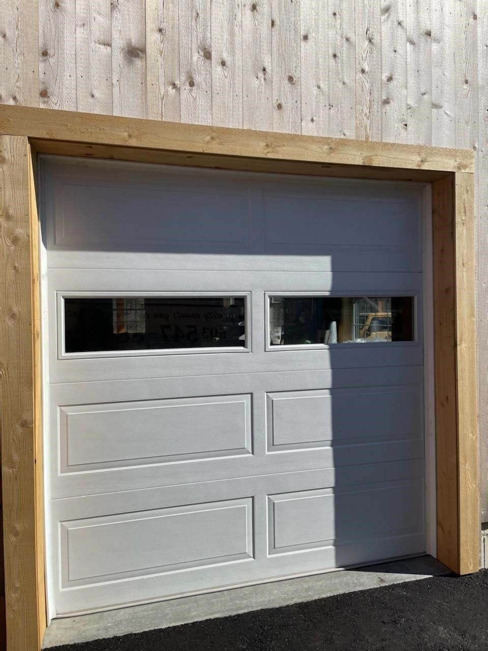 A white garage door with a wooden frame and a window.