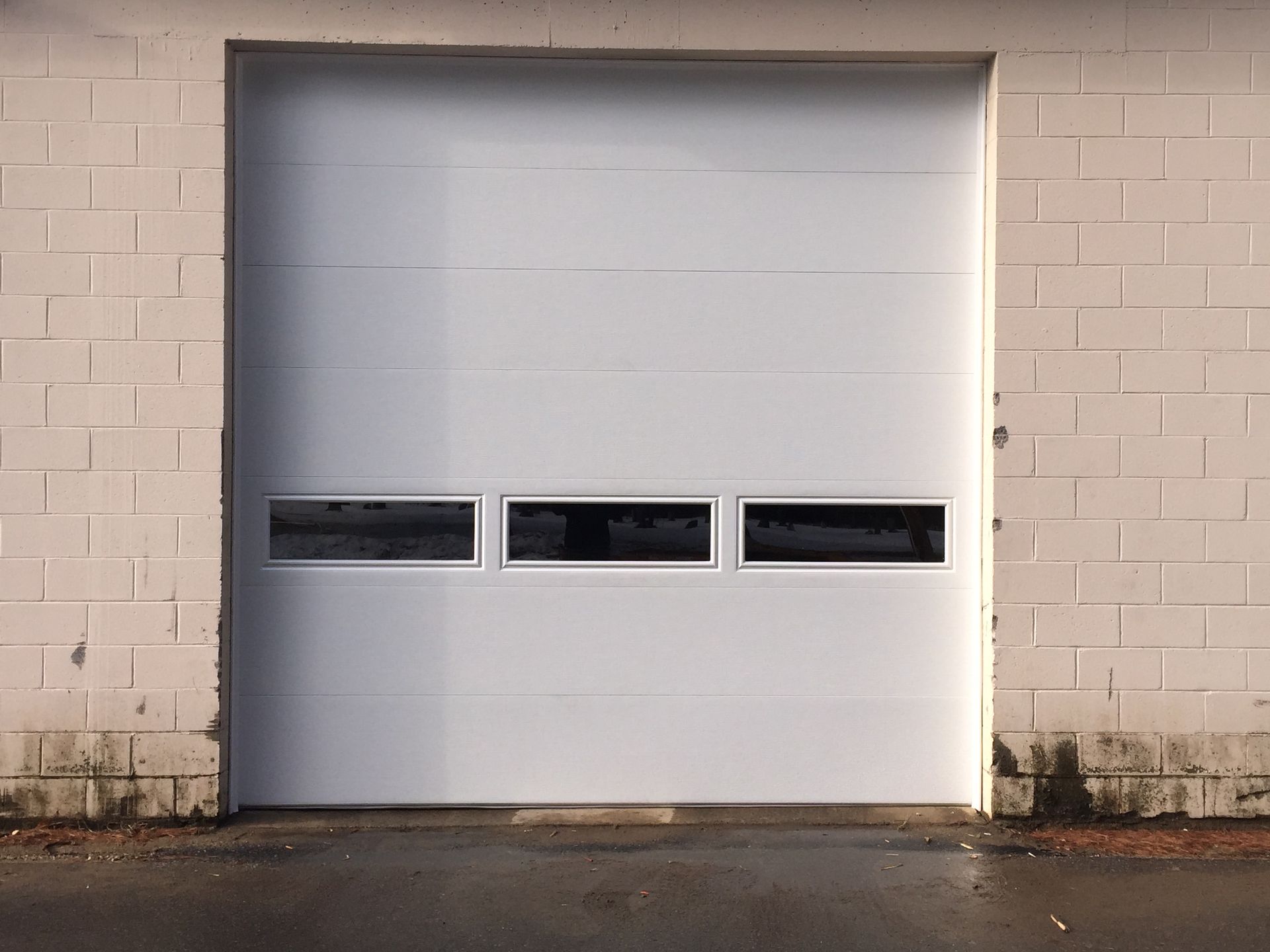 A white garage door with a brick wall behind it