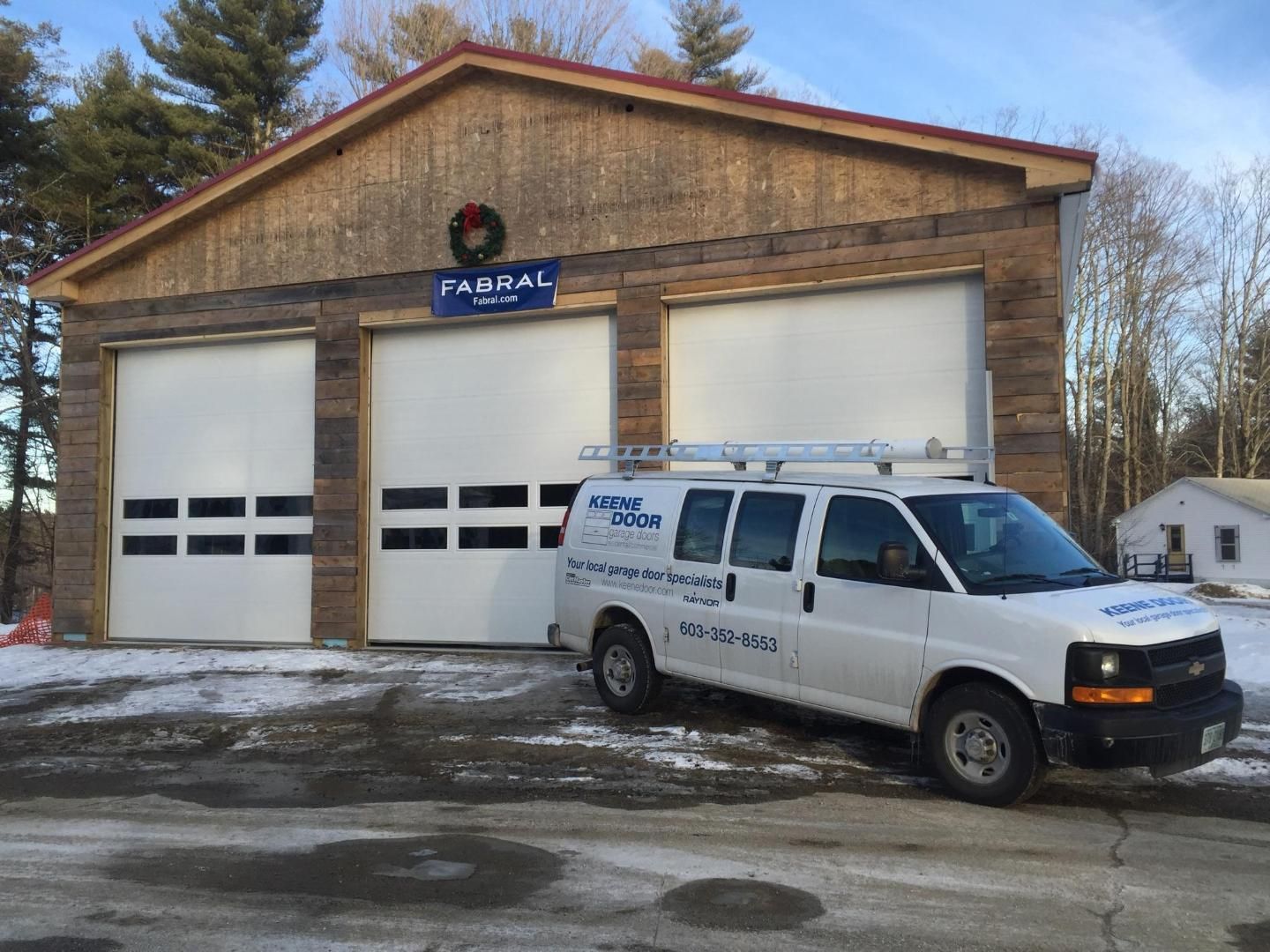 A white van is parked in front of a garage.