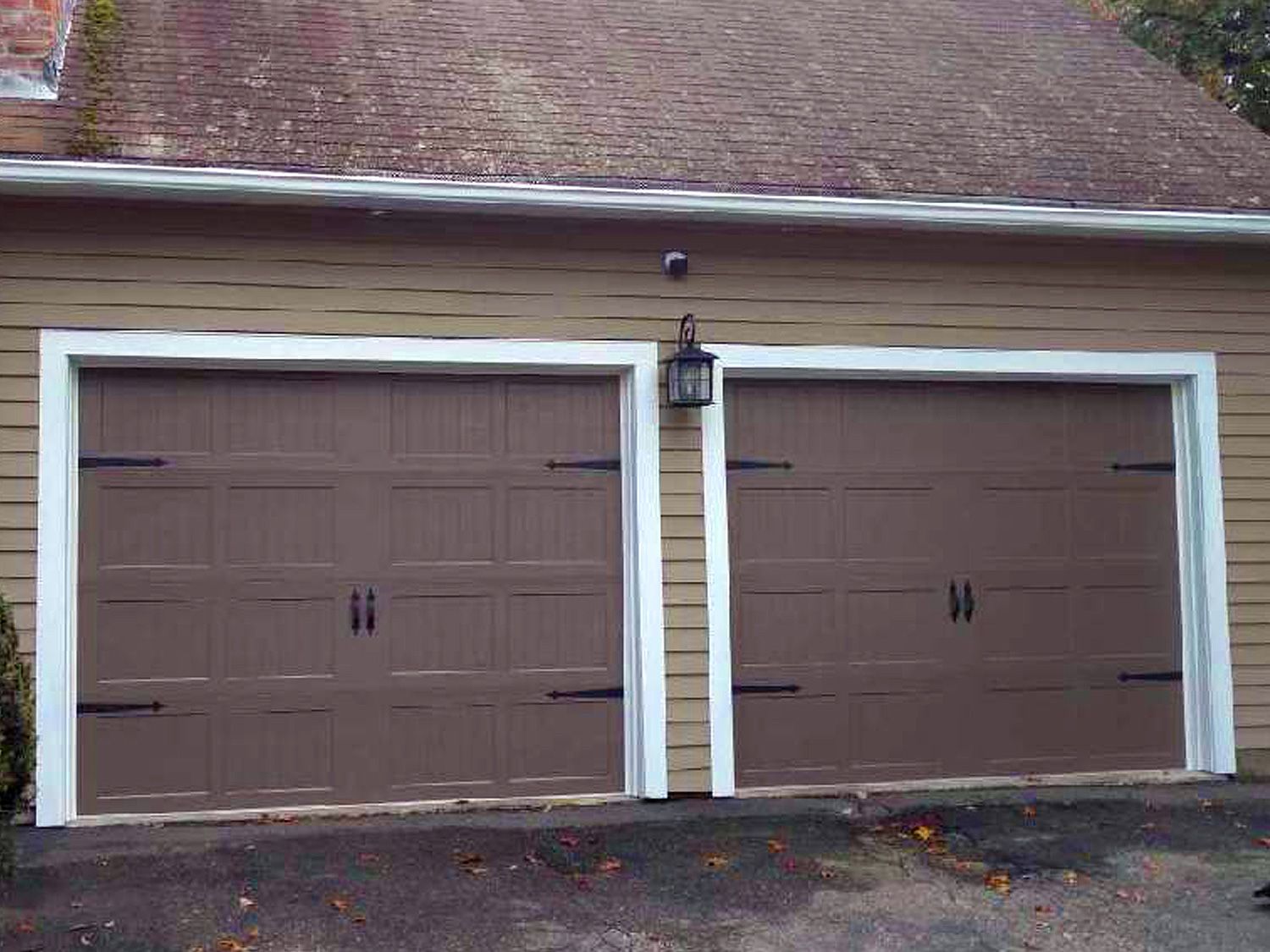 There are two garage doors on the side of a house.