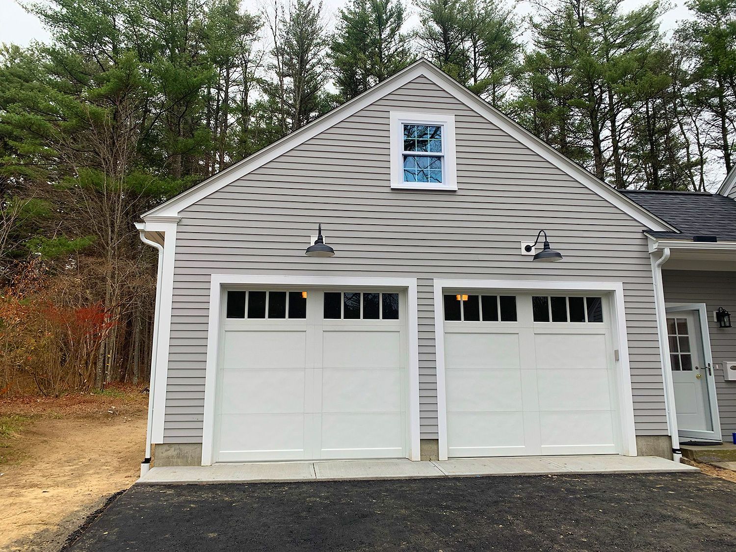 A garage with two white garage doors and a window.