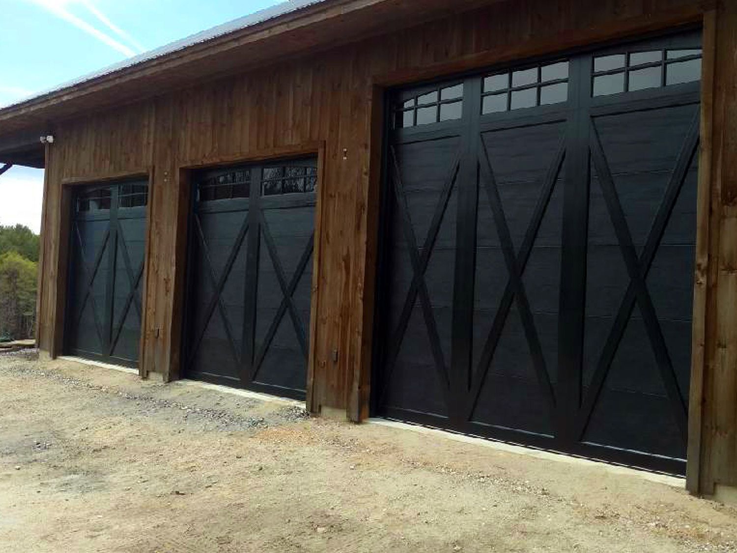 A row of black garage doors on a wooden building.