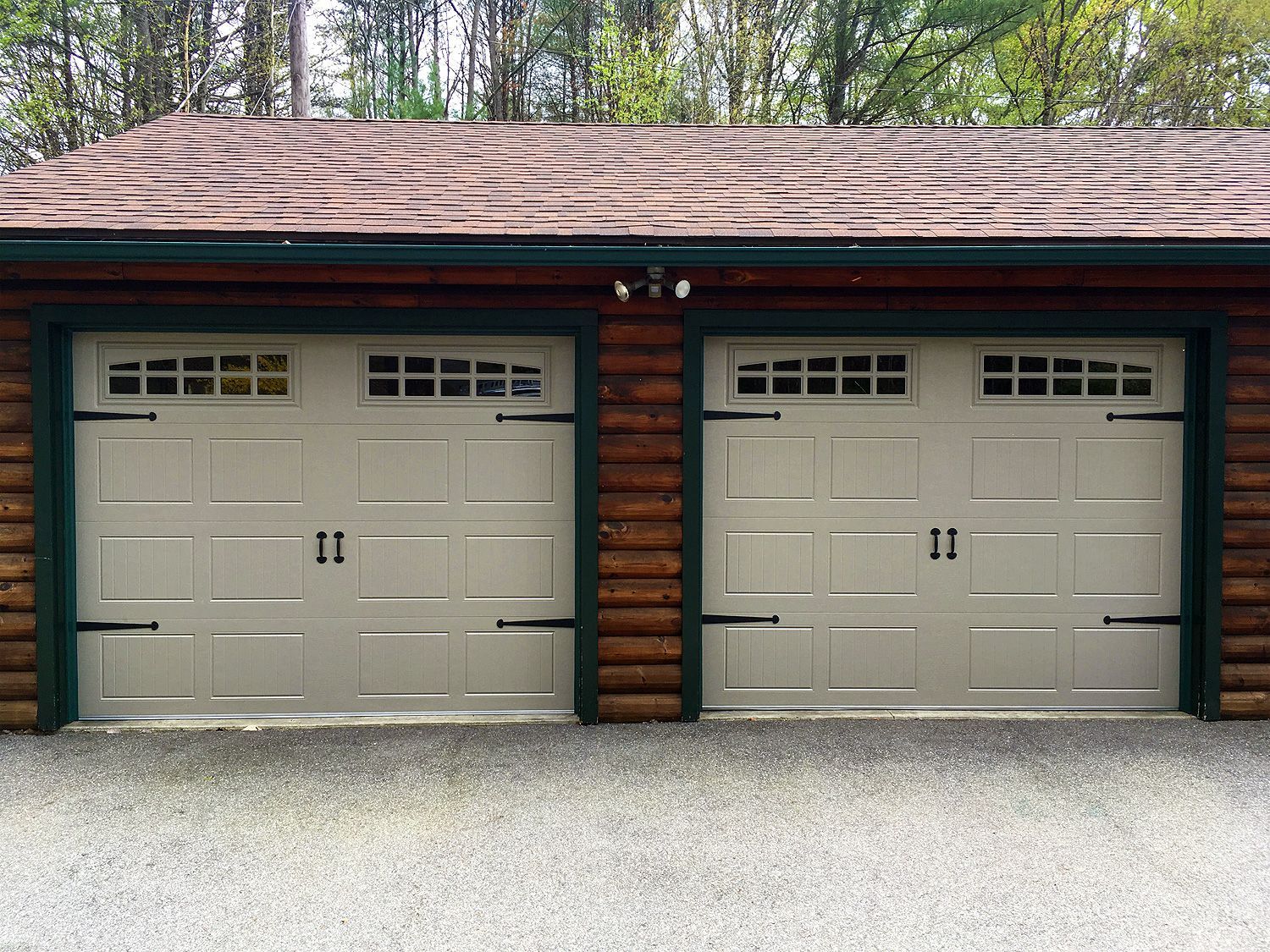 There are two garage doors on the side of a log cabin.