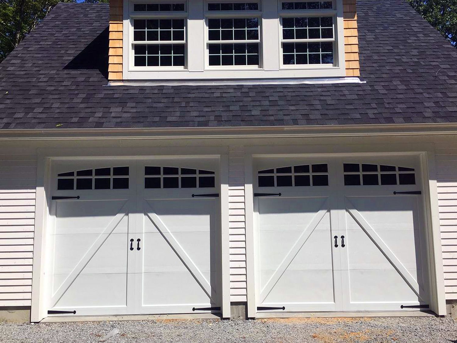 A garage with two white doors and a black roof