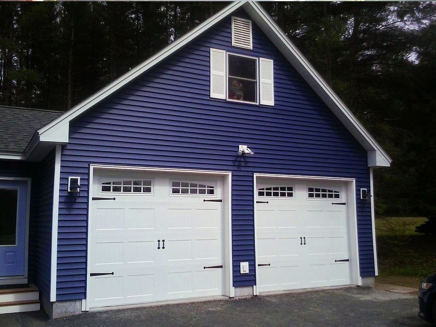 A blue garage with white doors and a window