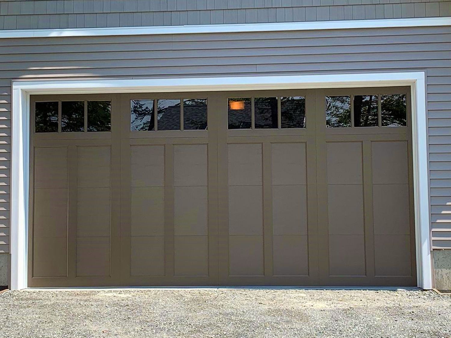 A tan garage door with a white trim and windows