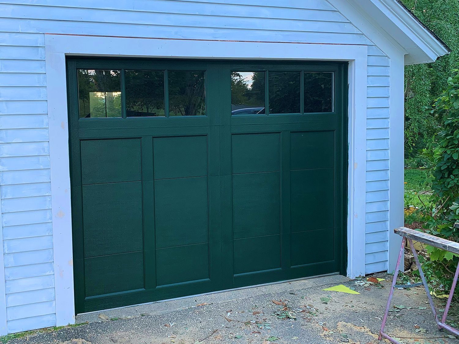 A green garage door is on a white building.