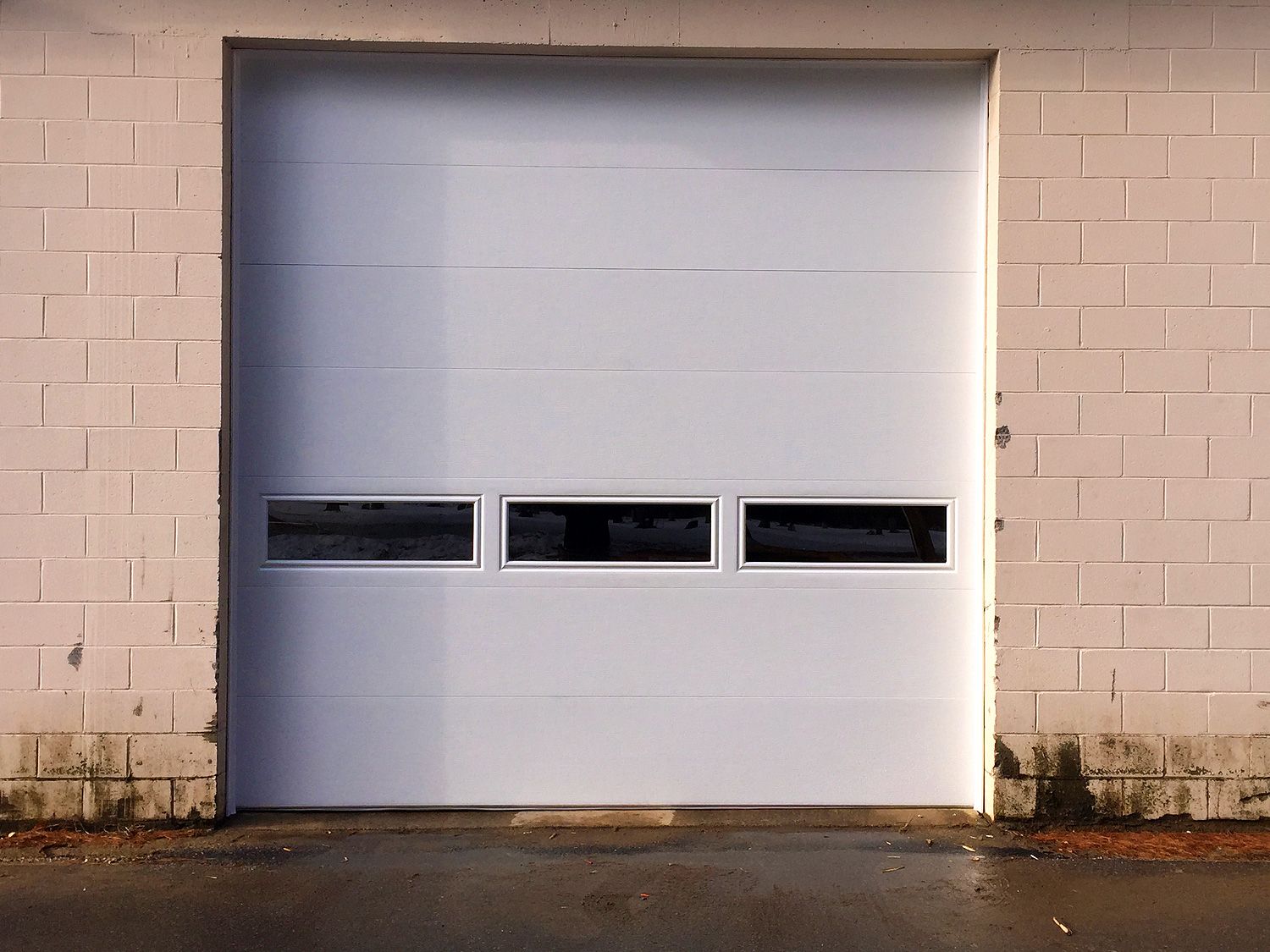 A white garage door with a brick wall behind it
