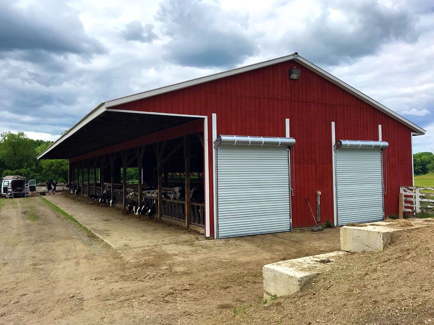 A large red barn with white doors on a cloudy day.