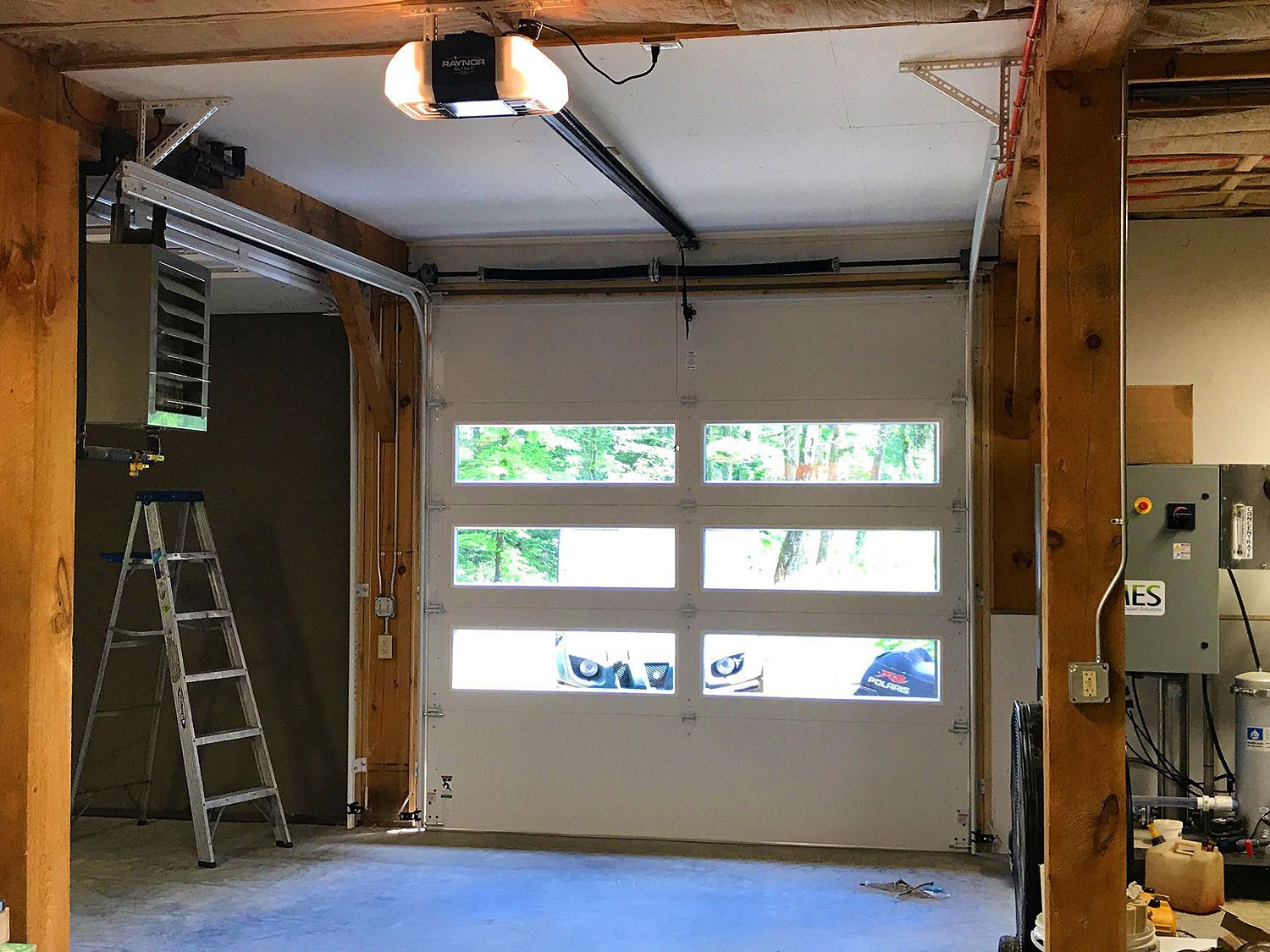 A garage with a ladder and a garage door open