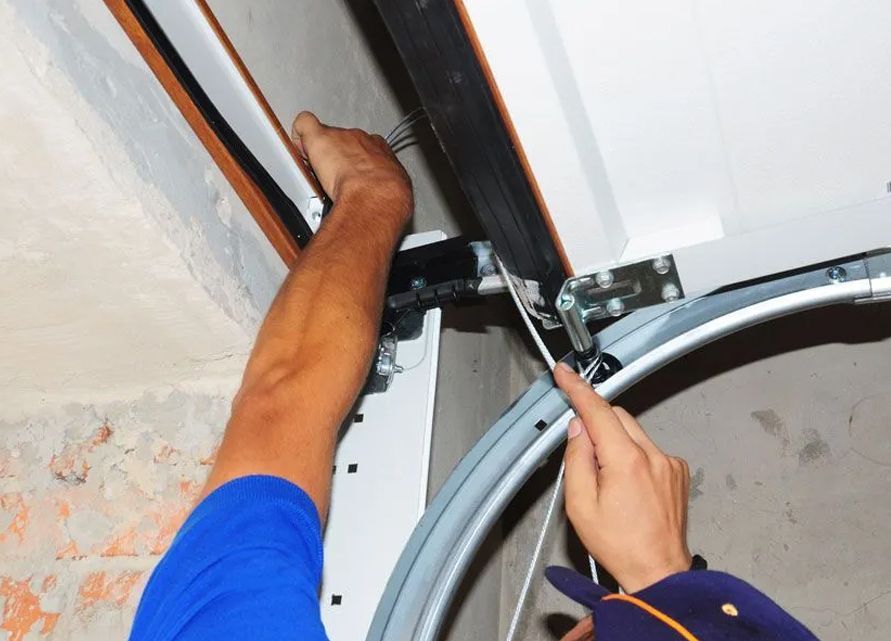 A man is fixing a garage door with a wrench.