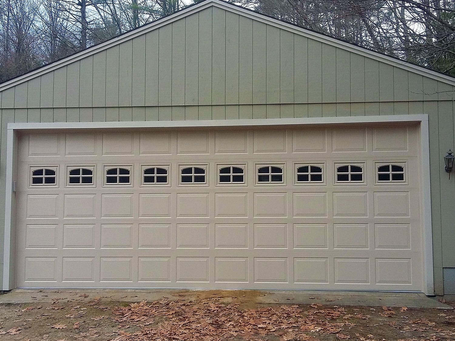 A large tan garage door with a green roof