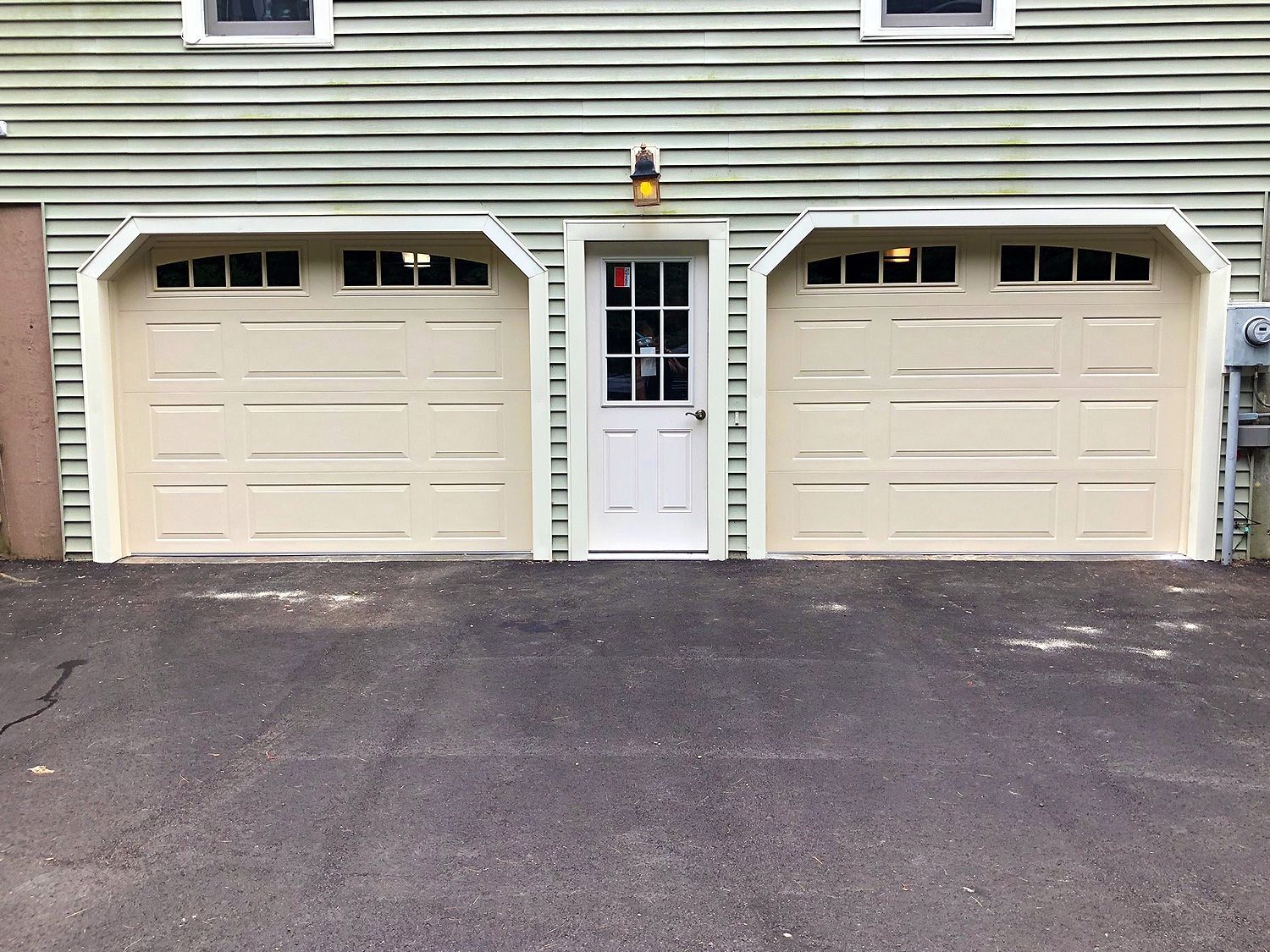 There are two garage doors and a door in front of a house.