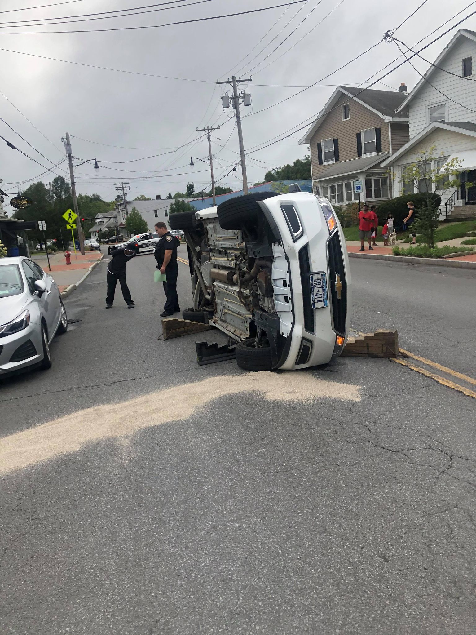 A car is on its side in the middle of a street.