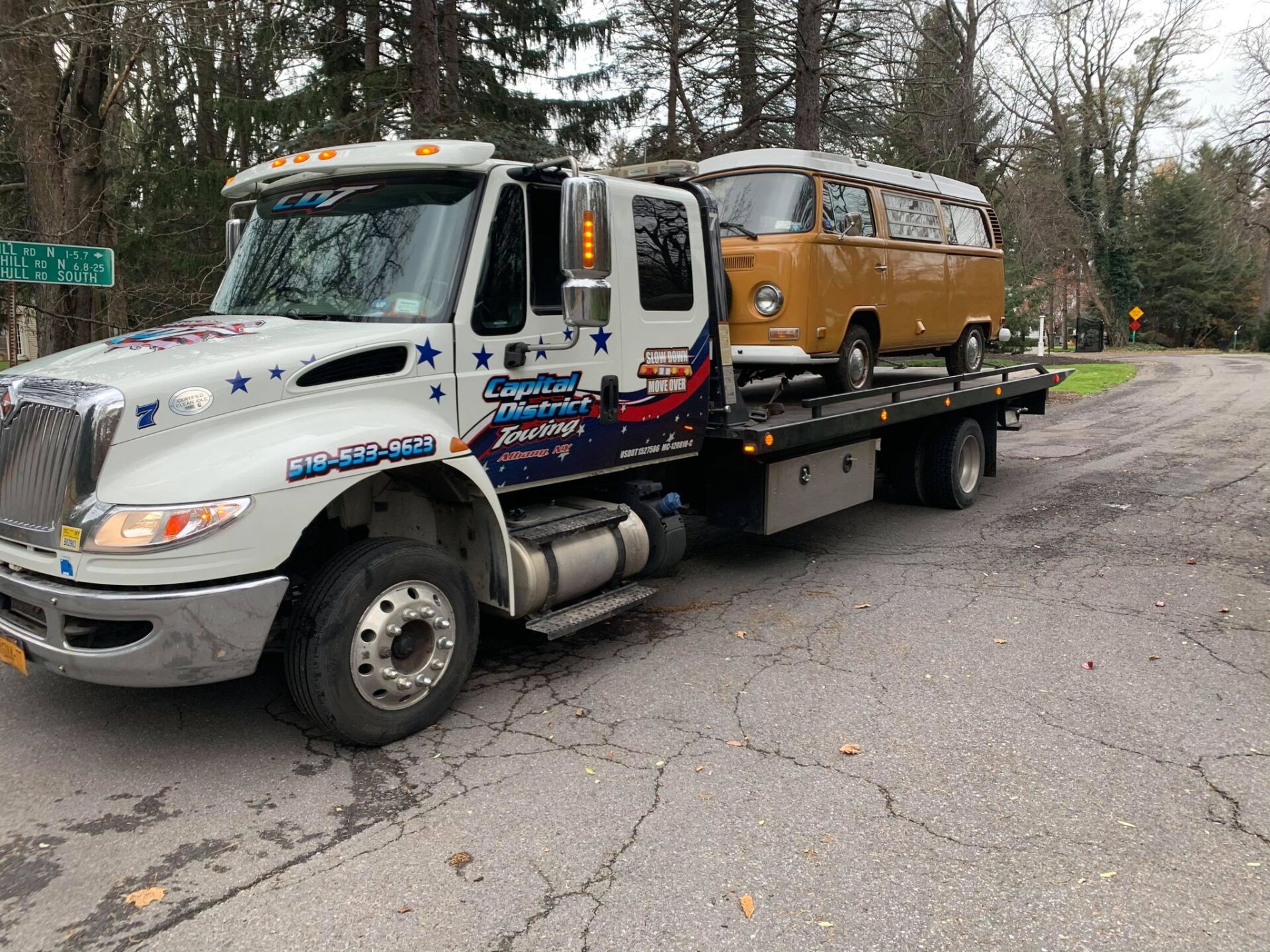 A tow truck is carrying a van on the back of it.