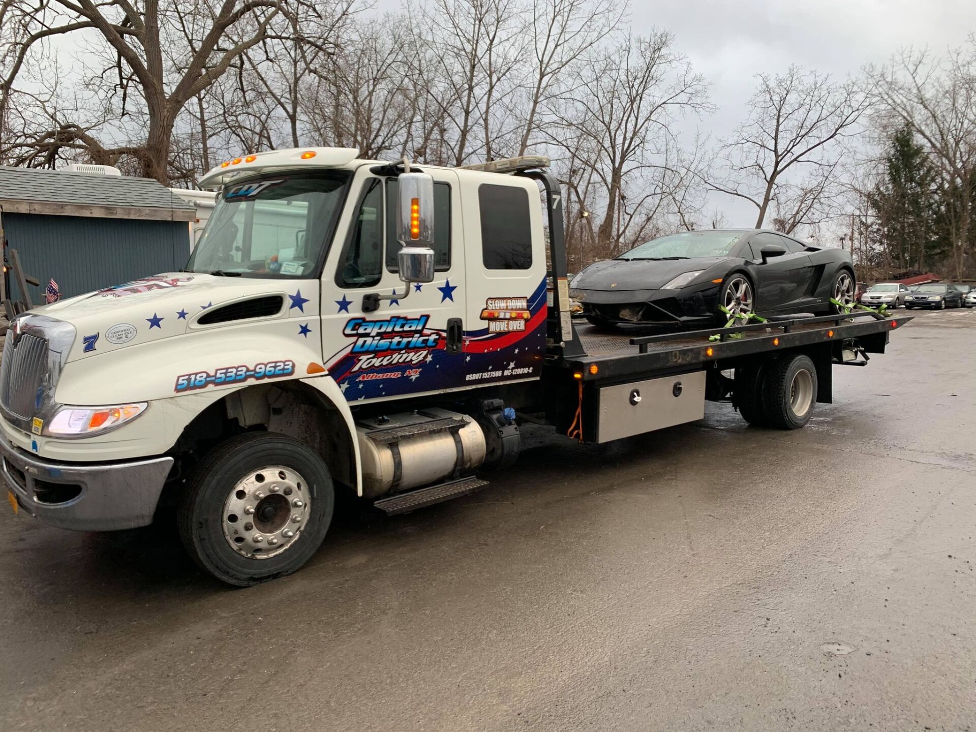 A tow truck with a car on the back is parked in a parking lot.