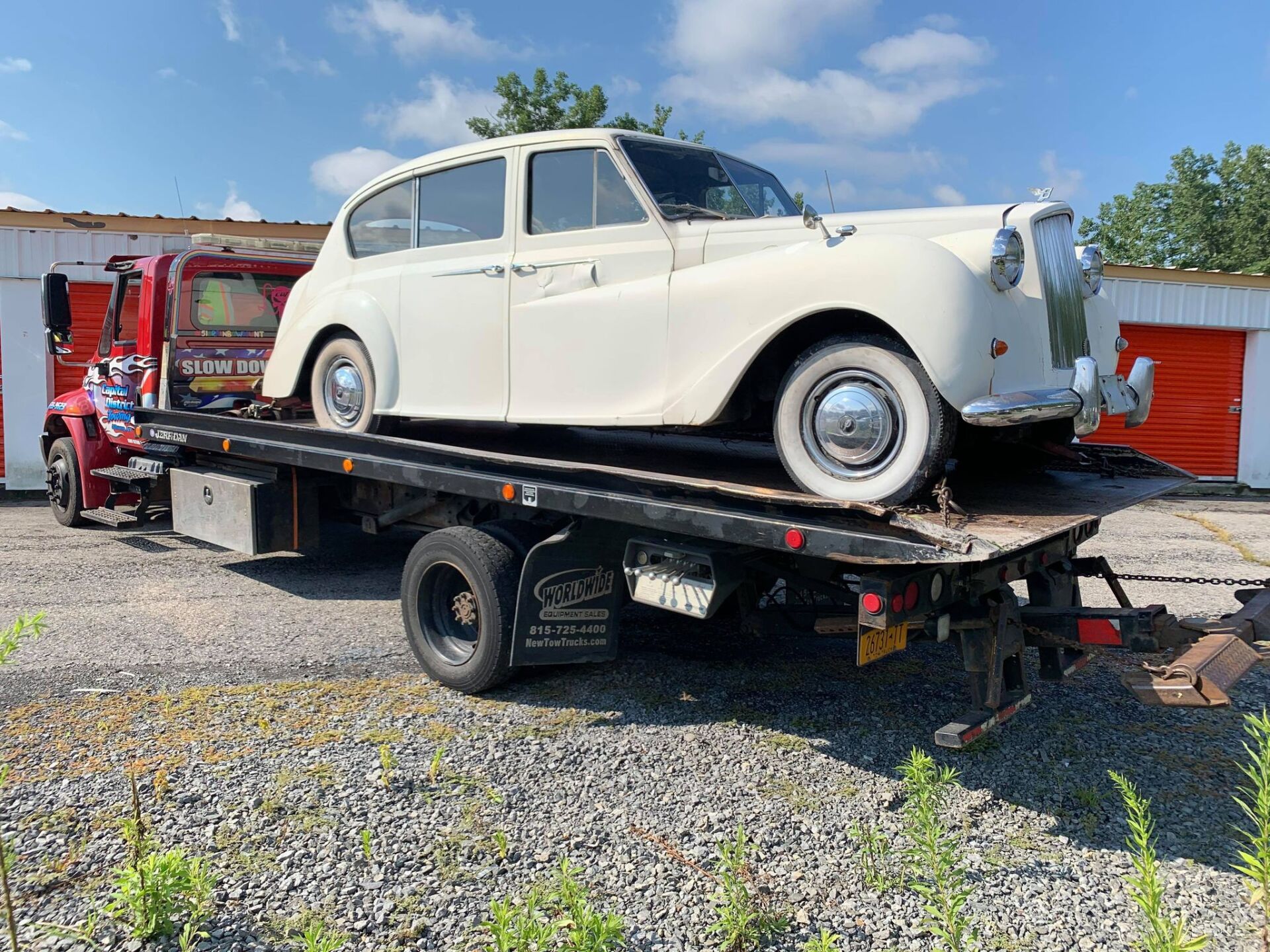 A white car is sitting on top of a tow truck.