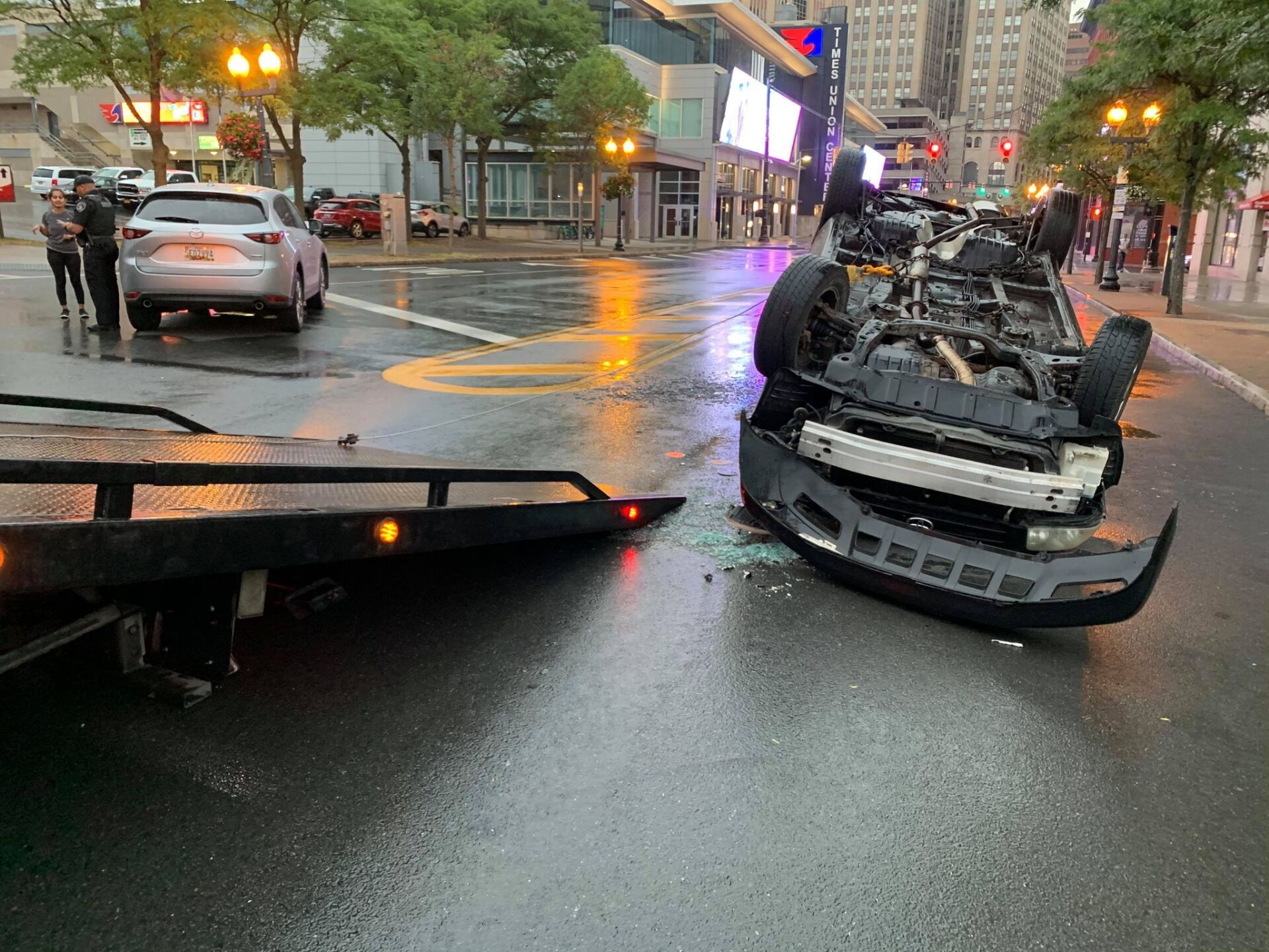 A car has fallen on its side on the side of the road.