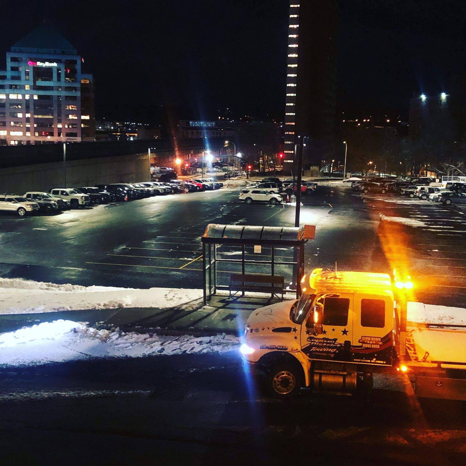 A tow truck is parked in a parking lot at night