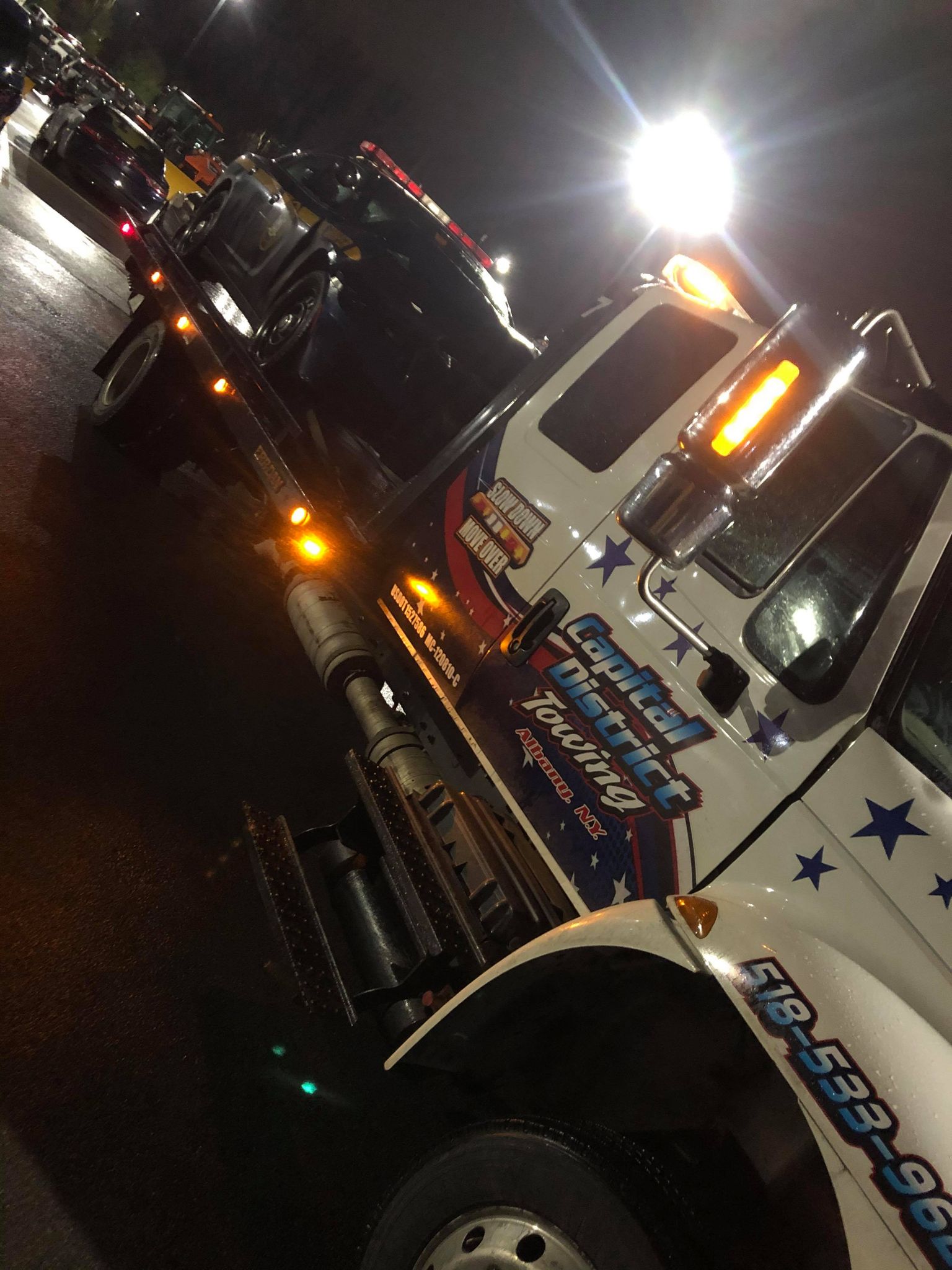 A tow truck is parked on the side of the road at night