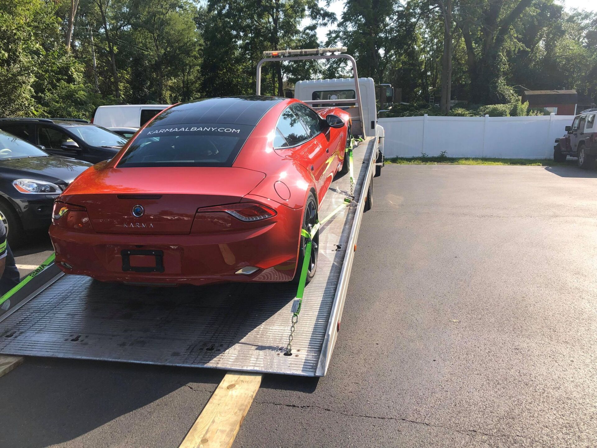 A red car is being towed by a tow truck