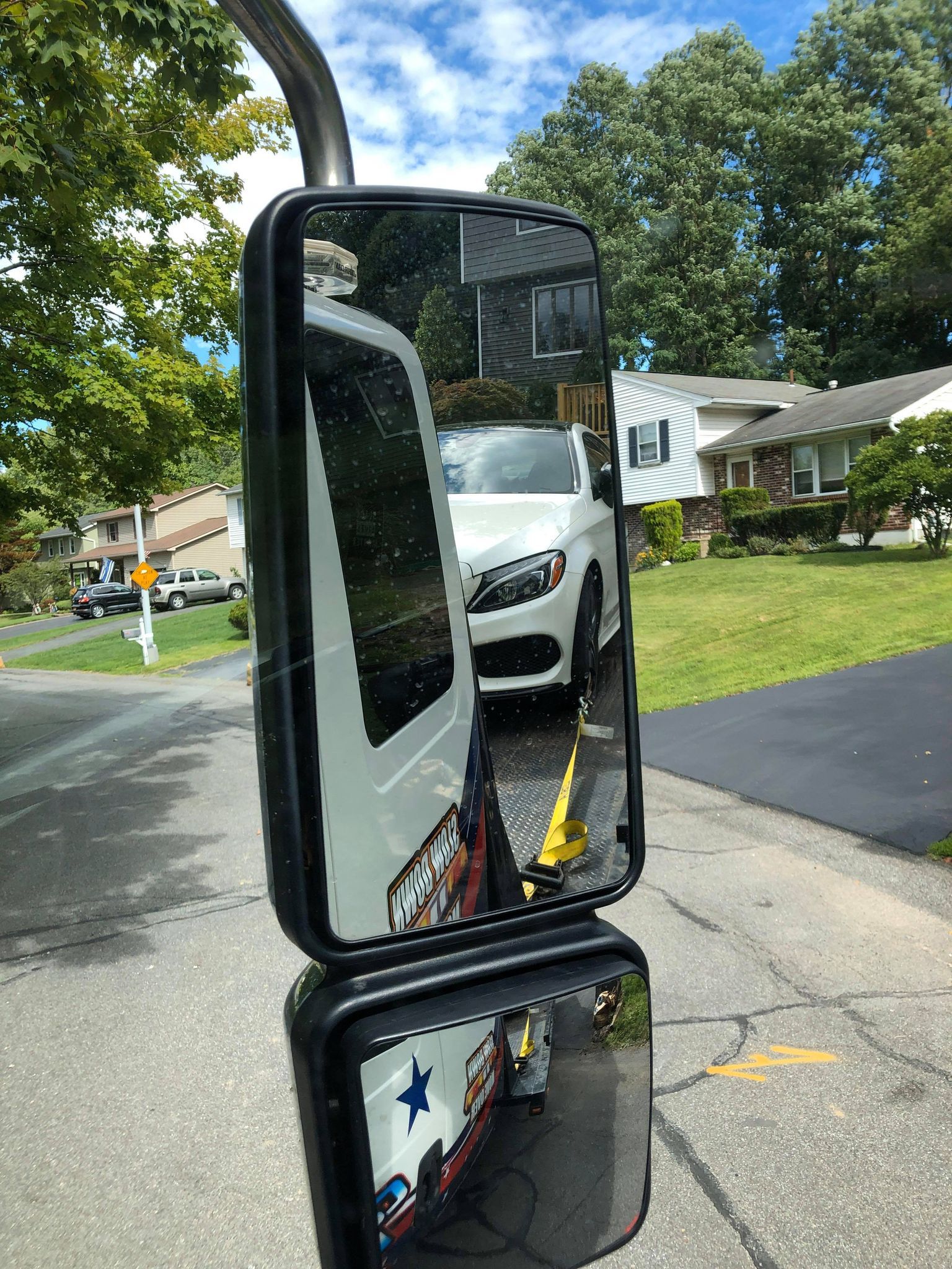 A car is reflected in a side view mirror on a street.