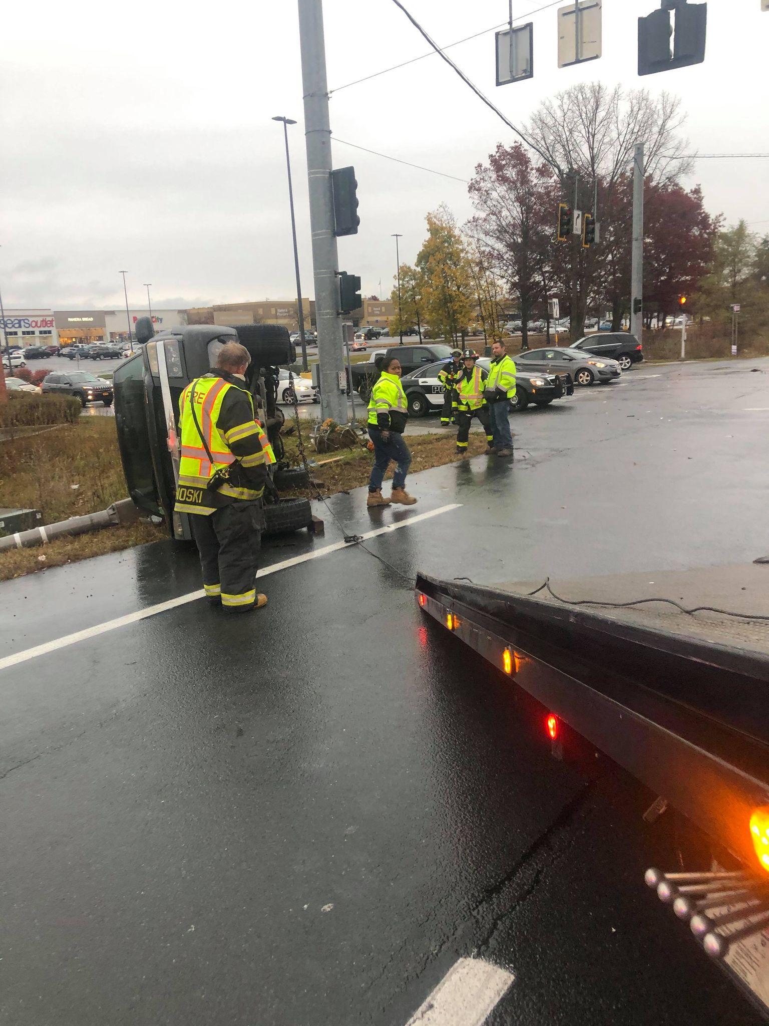 A group of firefighters are standing on the side of the road next to a tow truck.