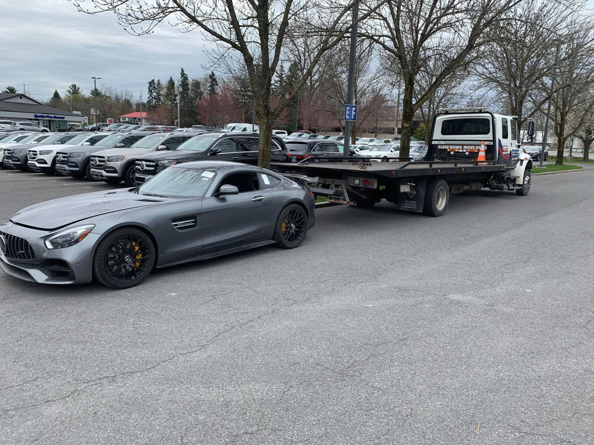 A car is being towed by a tow truck in a parking lot.