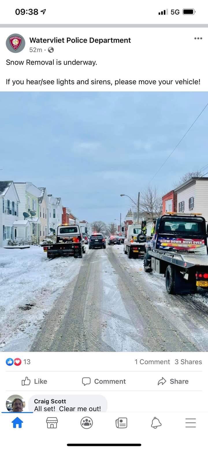 A tow truck is driving down a snowy street.