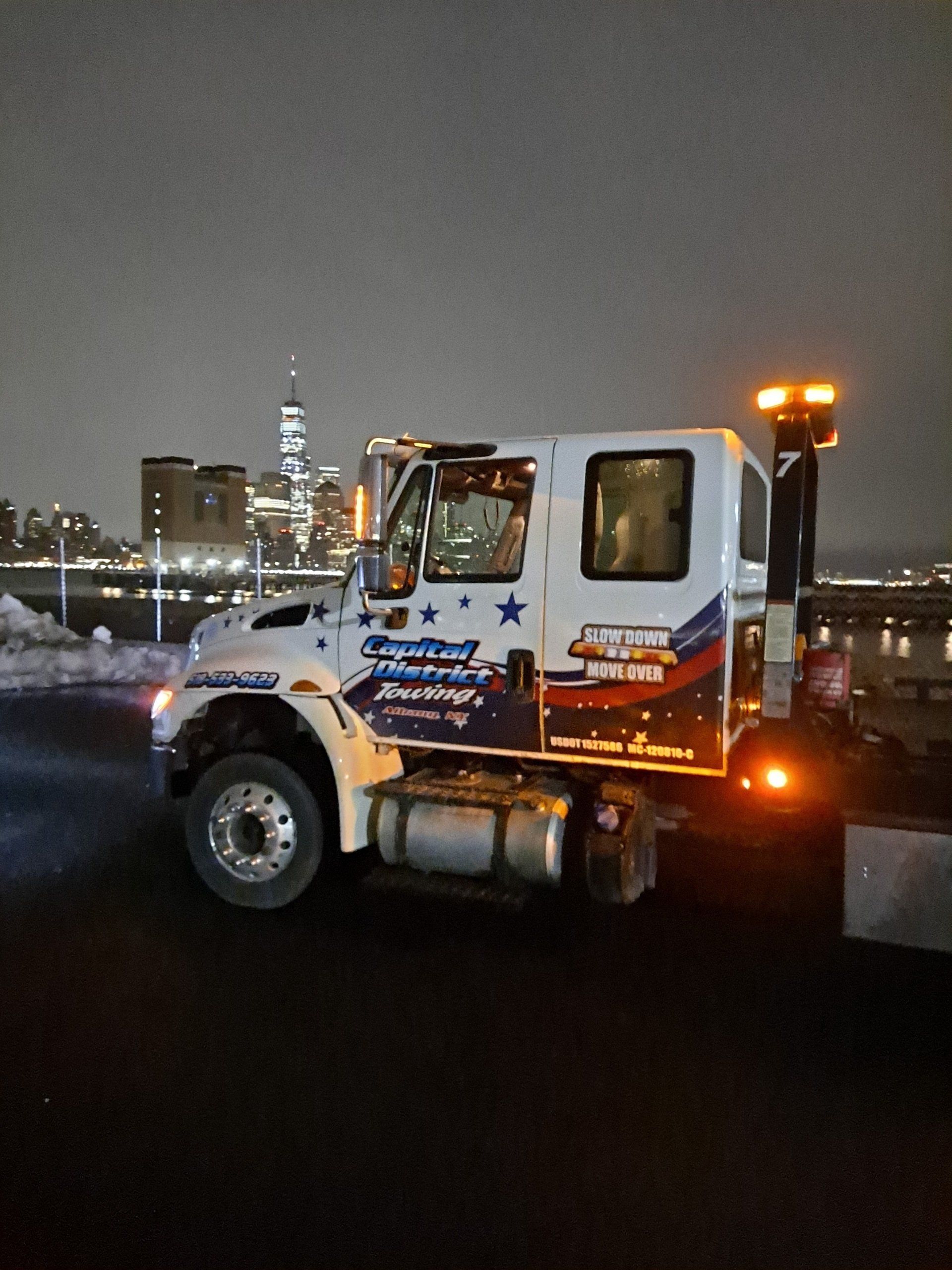 A tow truck is parked on the side of the road at night