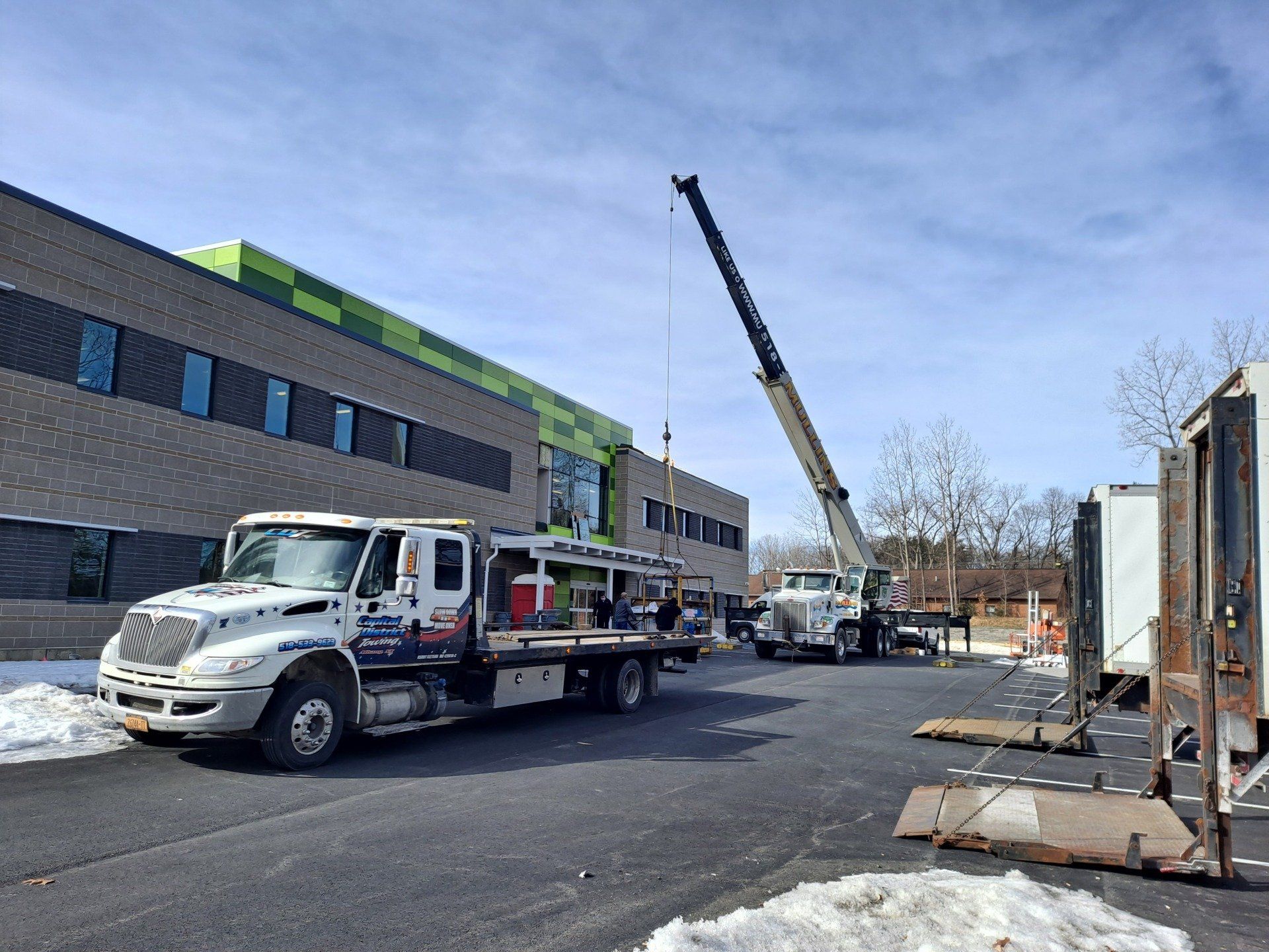 A tow truck with a crane on the back is parked in front of a building.