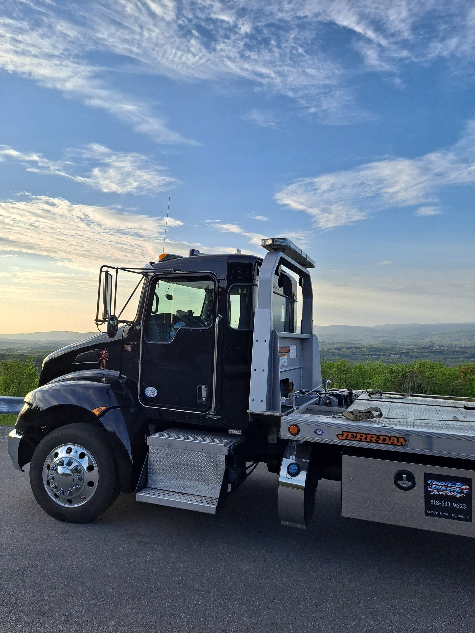 A black tow truck is parked on the side of the road.