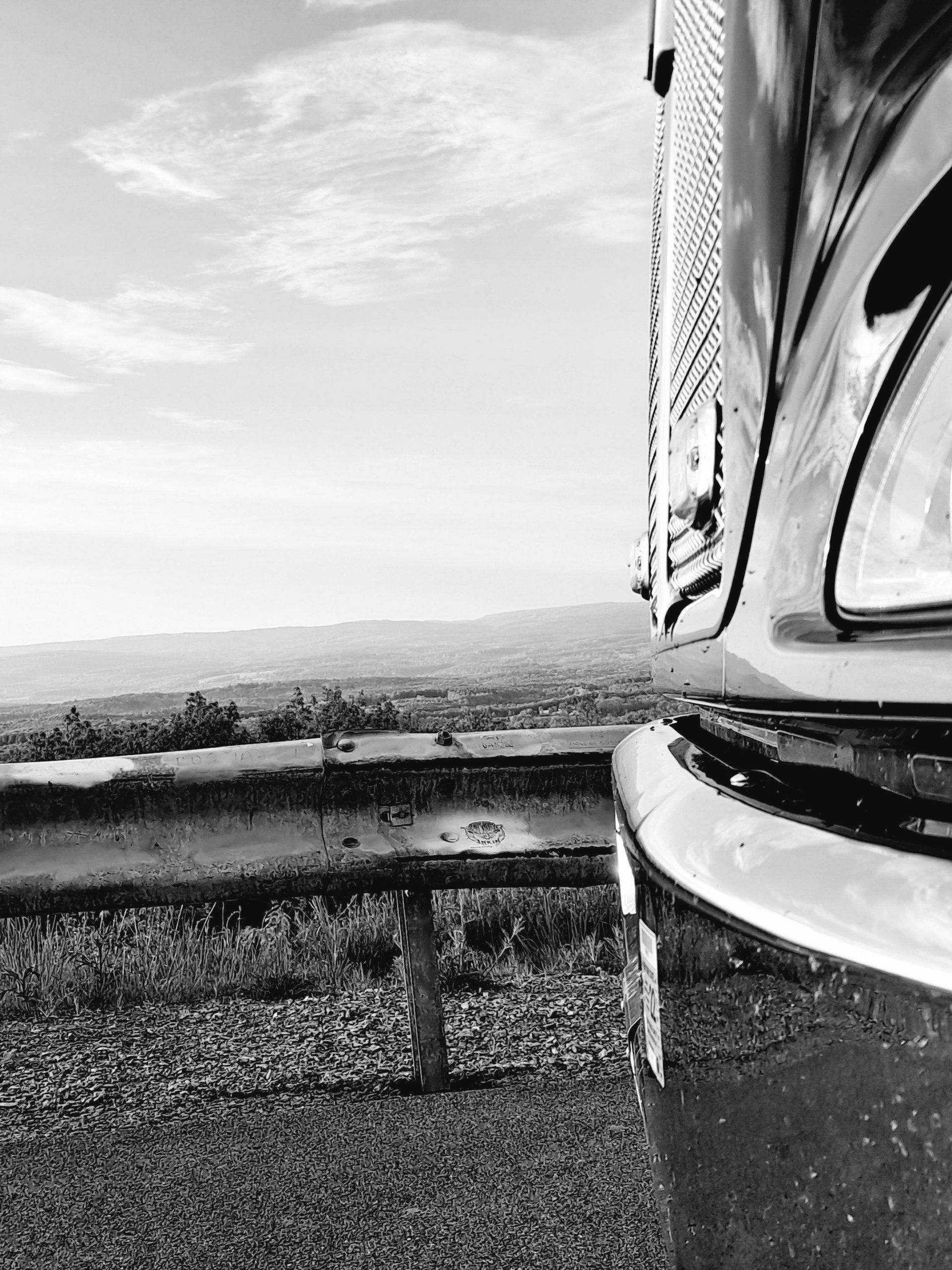A black and white photo of a truck parked on the side of a highway.