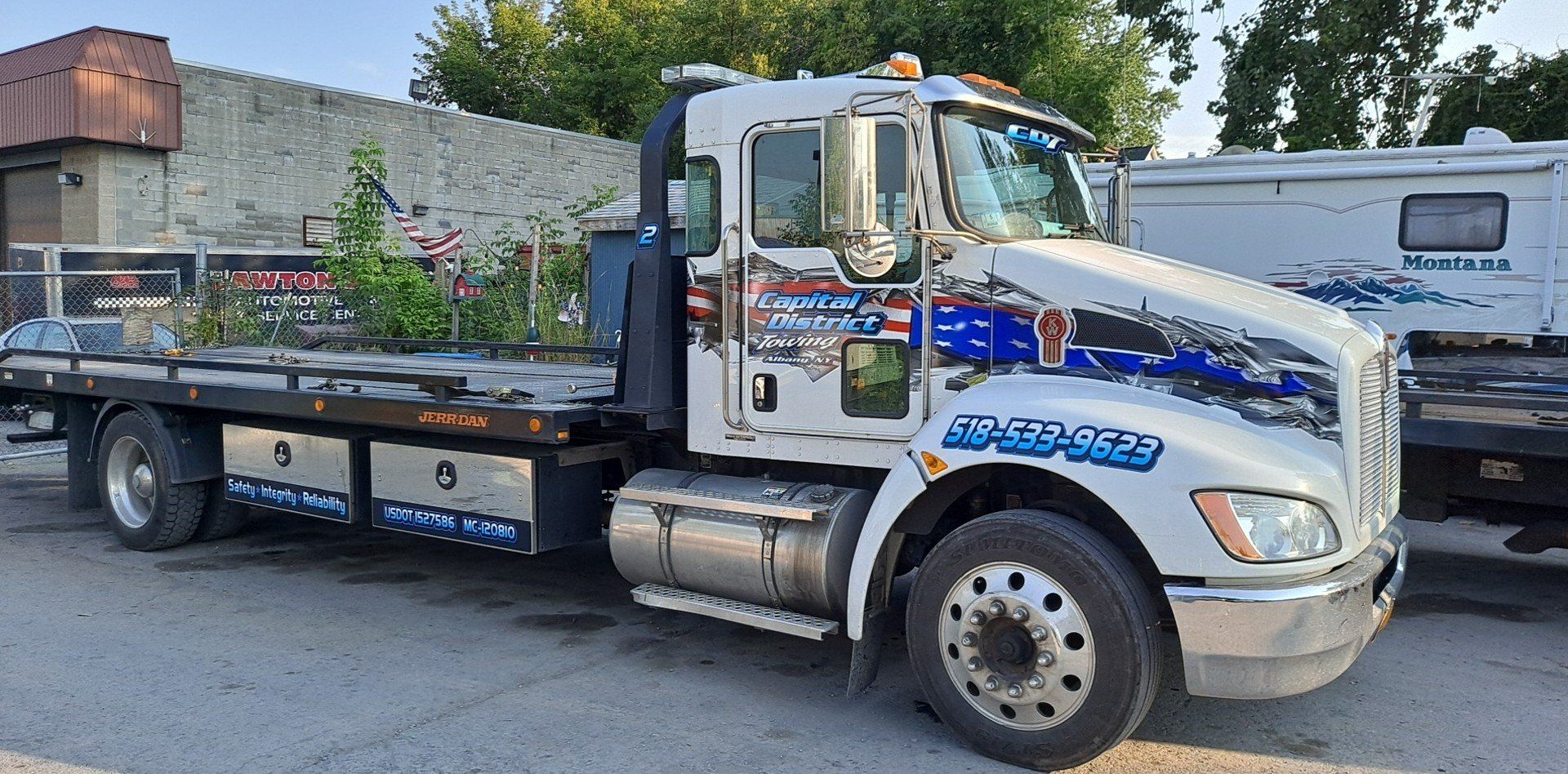 A white tow truck is parked on the side of the road.