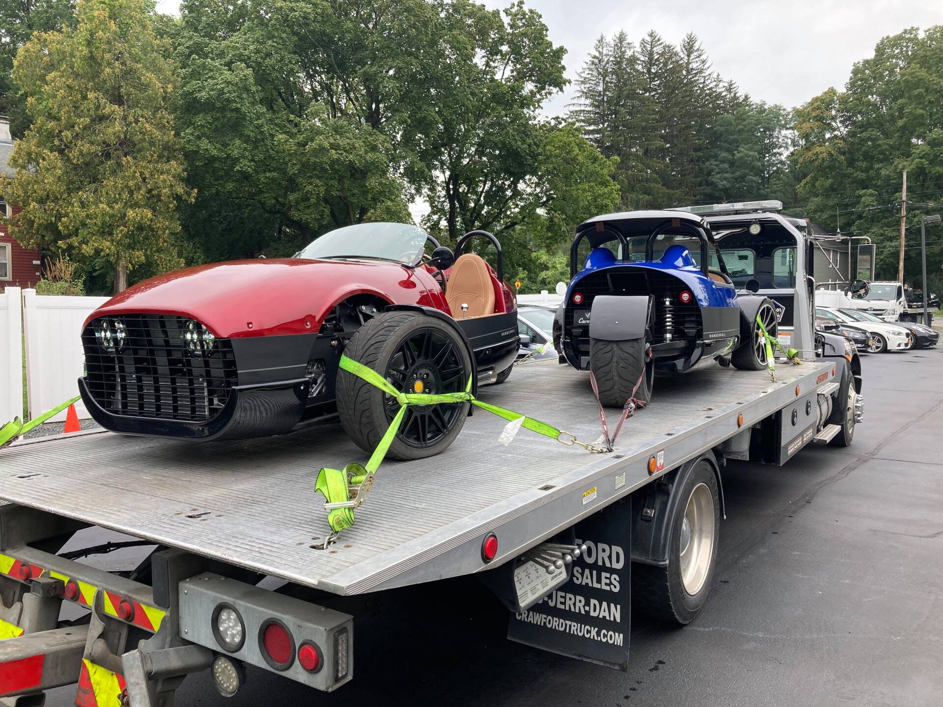 A red car is sitting on top of a tow truck.