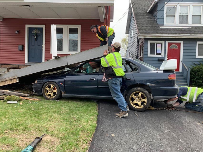 A car that has crashed into a house is being towed away.