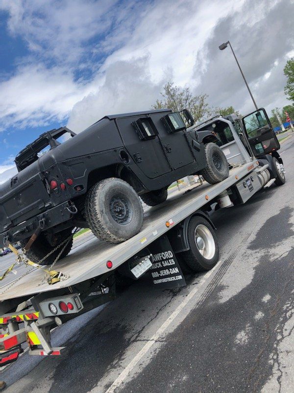 A black humvee is sitting on top of a tow truck.