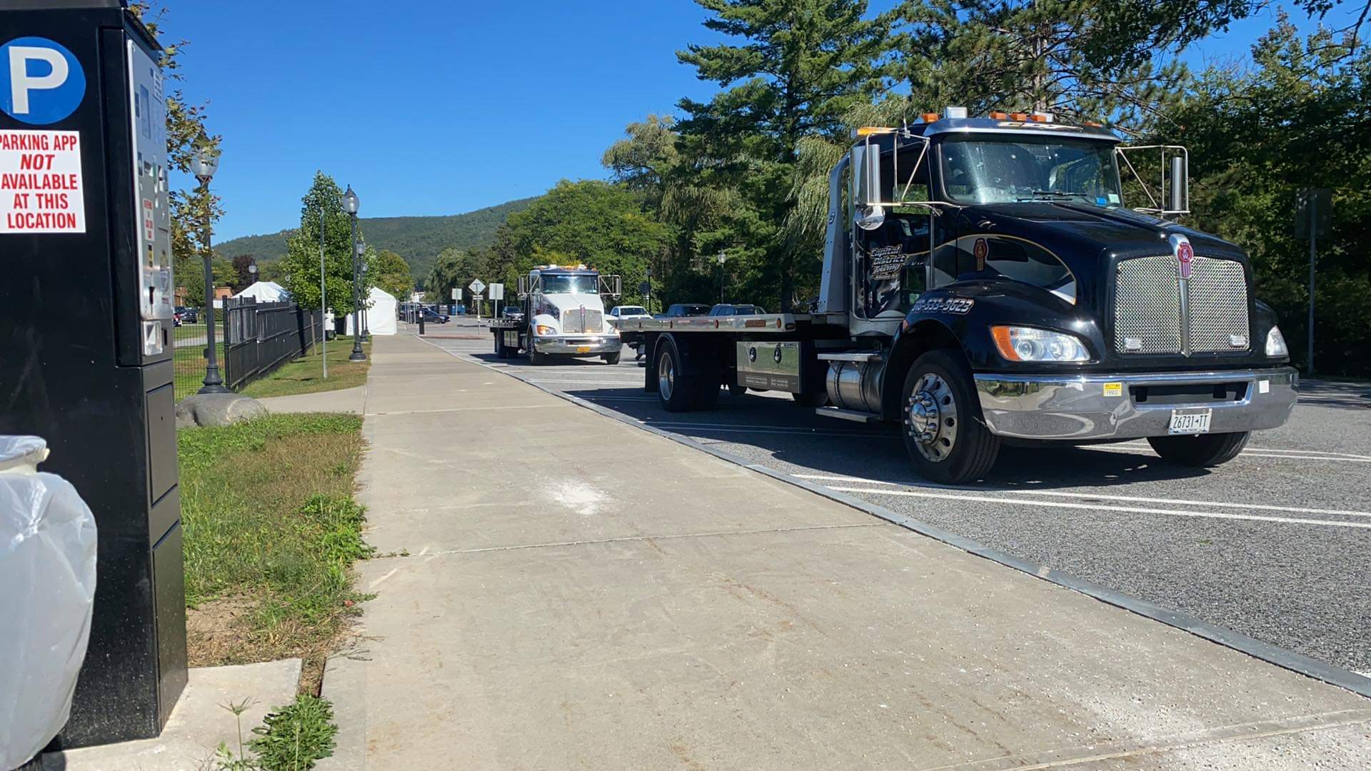 A tow truck is driving down a street next to a parking meter.