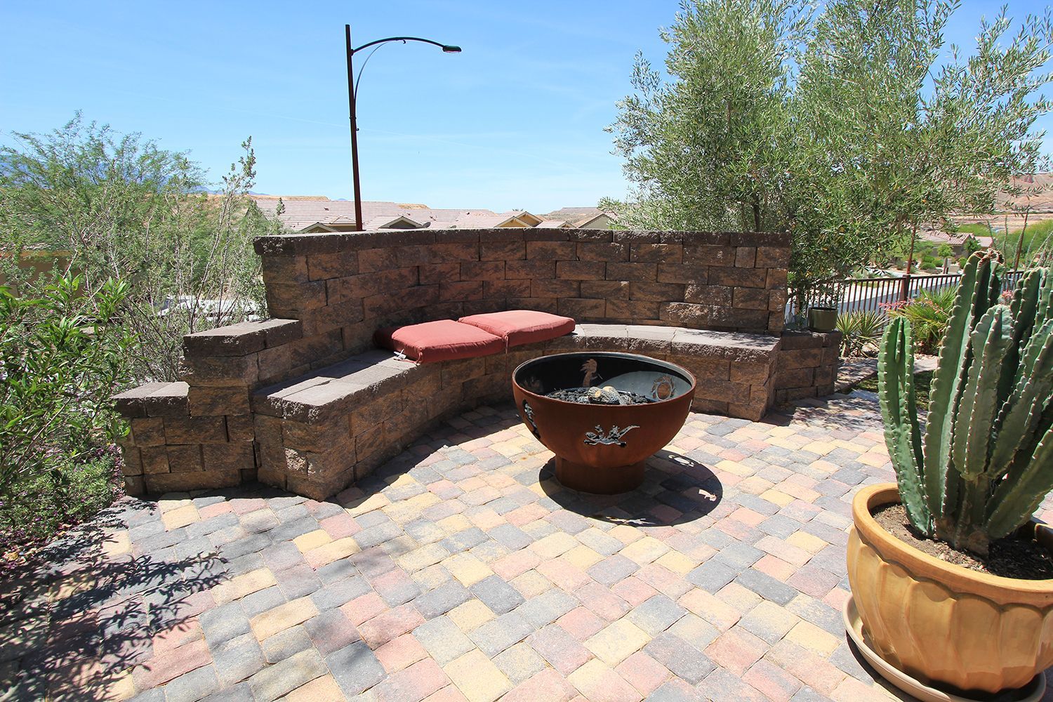 A brick patio with a fire pit and a bench
