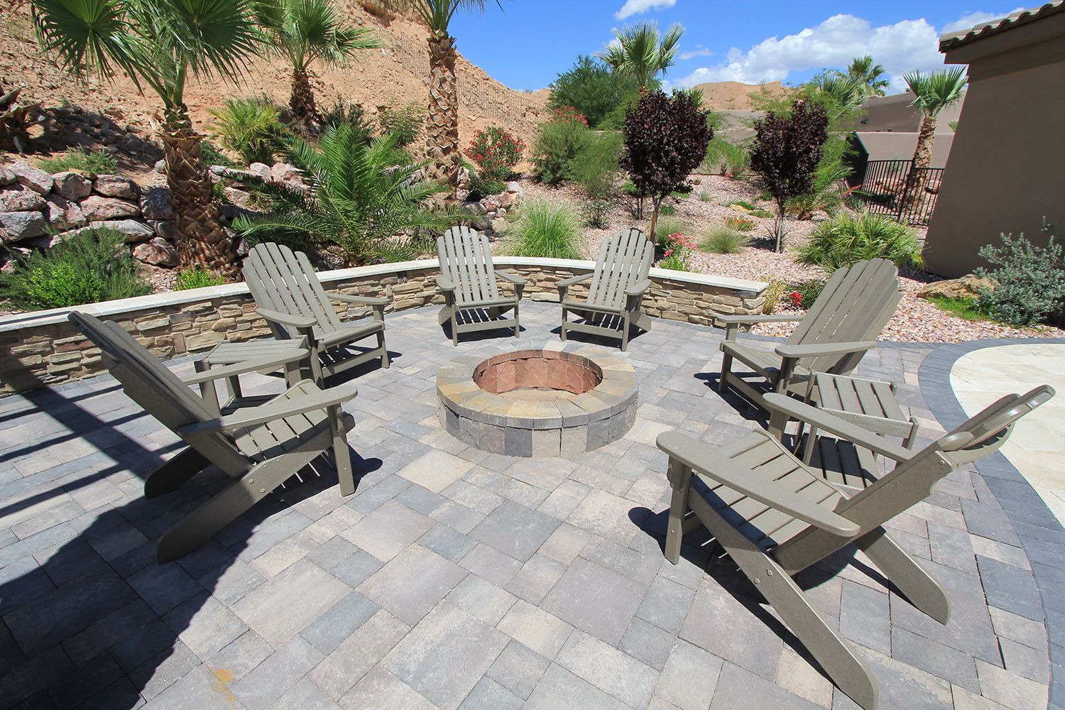 A fire pit is surrounded by chairs on a patio.