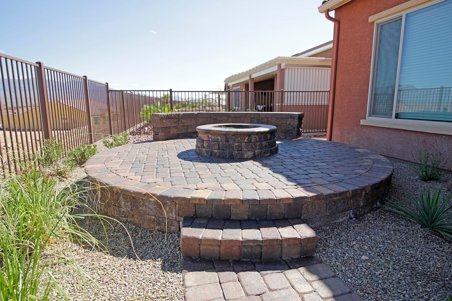 A fire pit is sitting on a brick patio in front of a house.