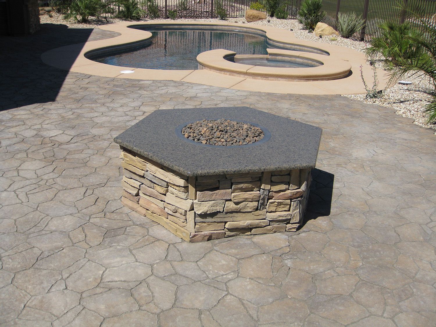 A fire pit sits on a patio next to a pool