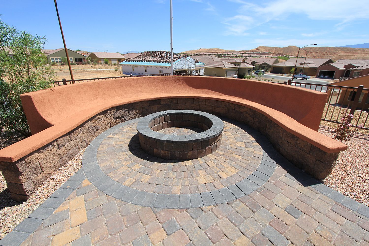 A fire pit is surrounded by bricks and a curved bench.
