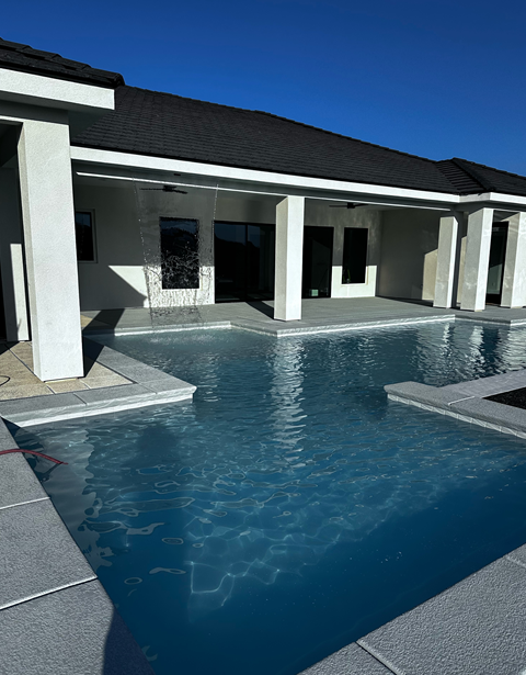 There is a large swimming pool in front of a house.